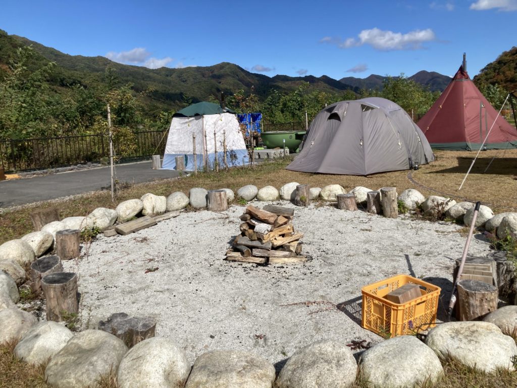 川原温泉駅キャンプ場の薪風呂とサウナ、直火OKな砂場、奥にあるのが手ぶらキャンプのテント