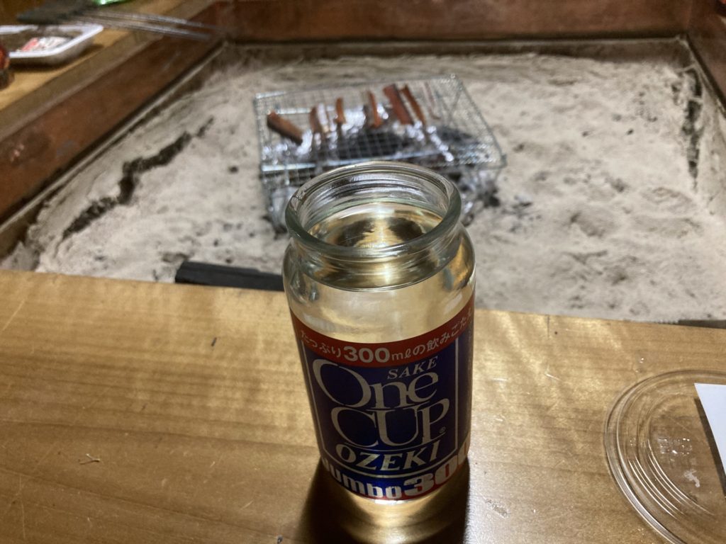 十文字ビレッジキャンプ場、ログハウス内の囲炉裏で鮭とばを炙りワンカップ酒