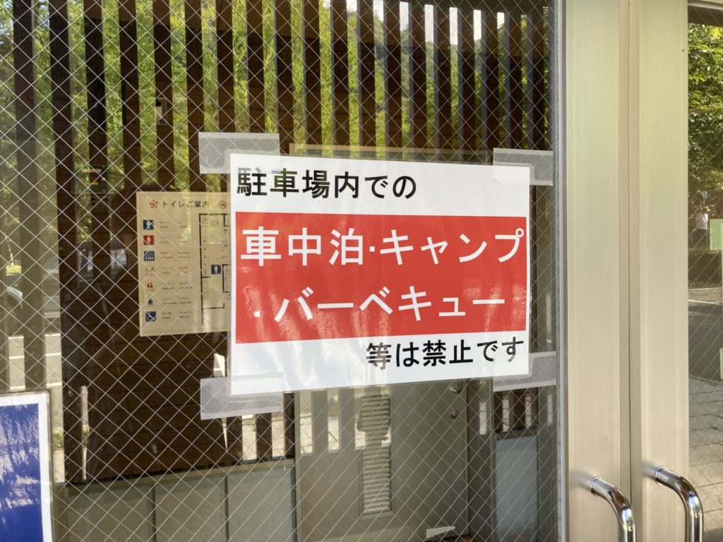 中禅寺湖の歌ヶ浜第一駐車場のトイレの入口壁と入口のドア、およびトイレ内にも車中泊禁止の張り紙が