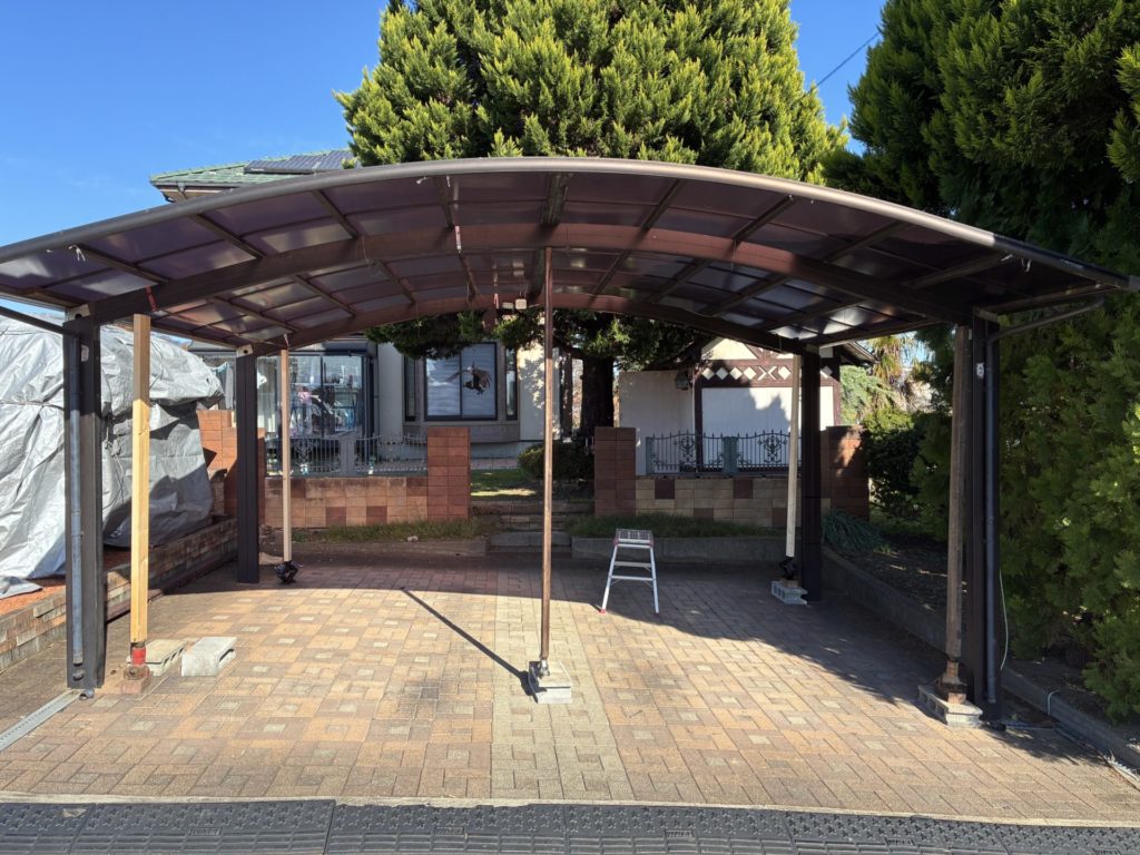 昭和アルミのカーポートの高さ調整DIYで20cmアップ途中でジャッキが伸びきったので真ん中に支柱を入れてジャッキの下にブロックを入れ高さ再調整をするところ(手前)